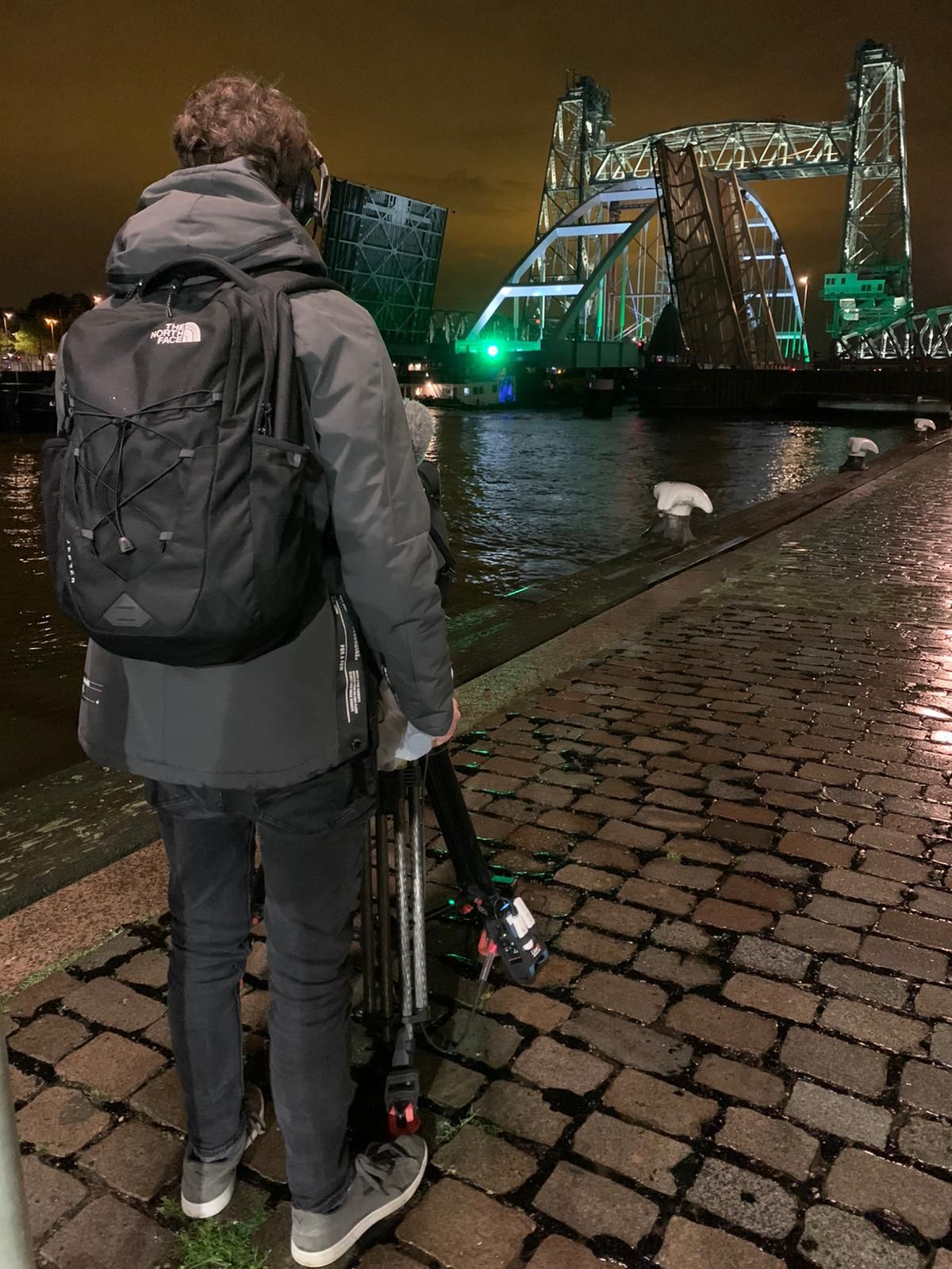 Een camera operator langs de kade bij de passage van de Hef en de Koninginnebrug.